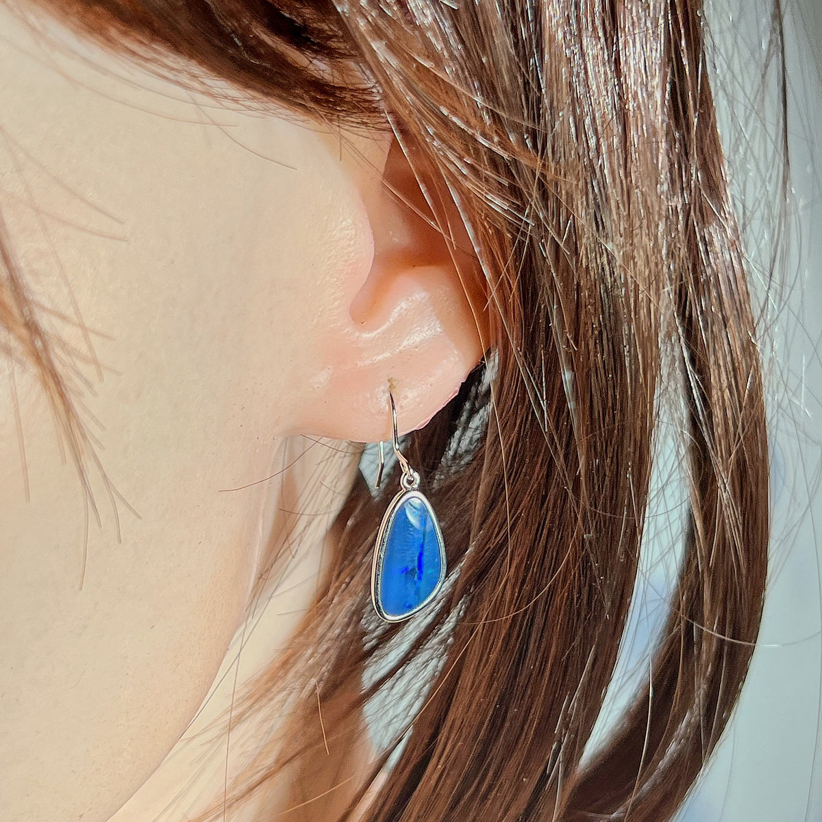 Australian opal doublet earrings worn on the ear, blue and green play-of-colour