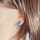 Opal doublet stud earring in silver worn on the ear, close view of the play-of-colour