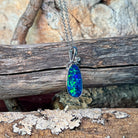 Freeform opal doublet pendant in silver showing bright green flash across the stone