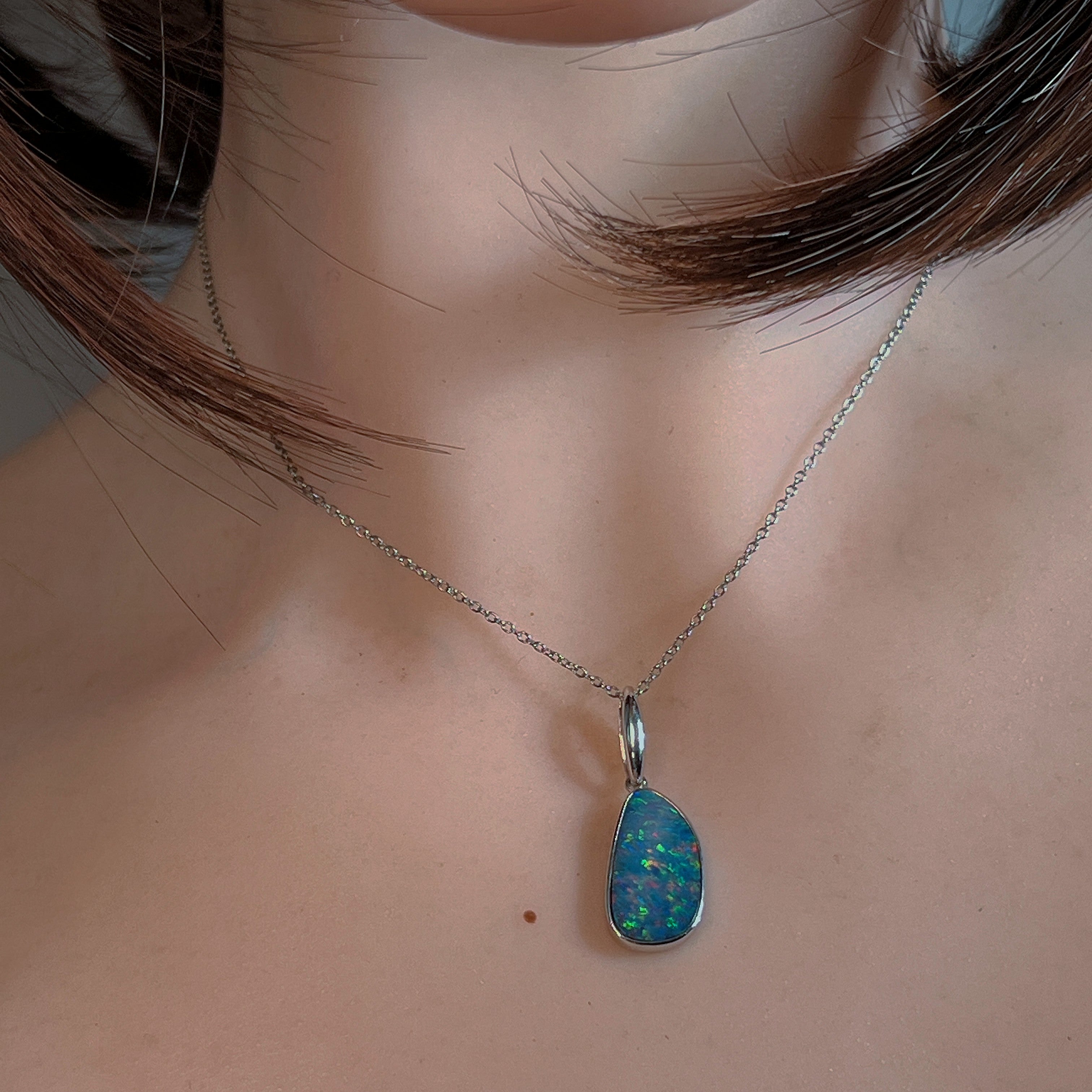 Opal doublet pendant with red and blue play-of-colour worn at the neck, close view