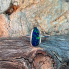 Elongated freeform opal doublet ring in silver resting on weathered driftwood