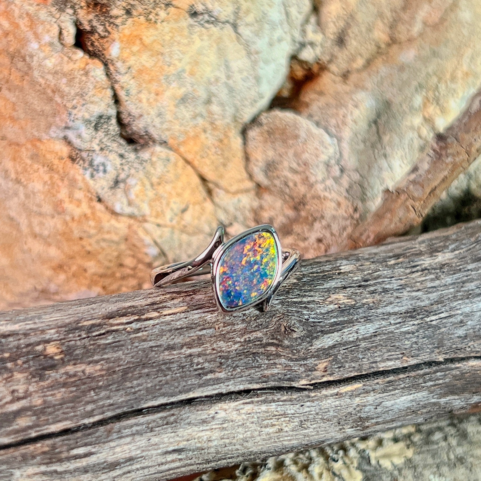Marquise opal doublet ring in silver on driftwood against Australian sandstone