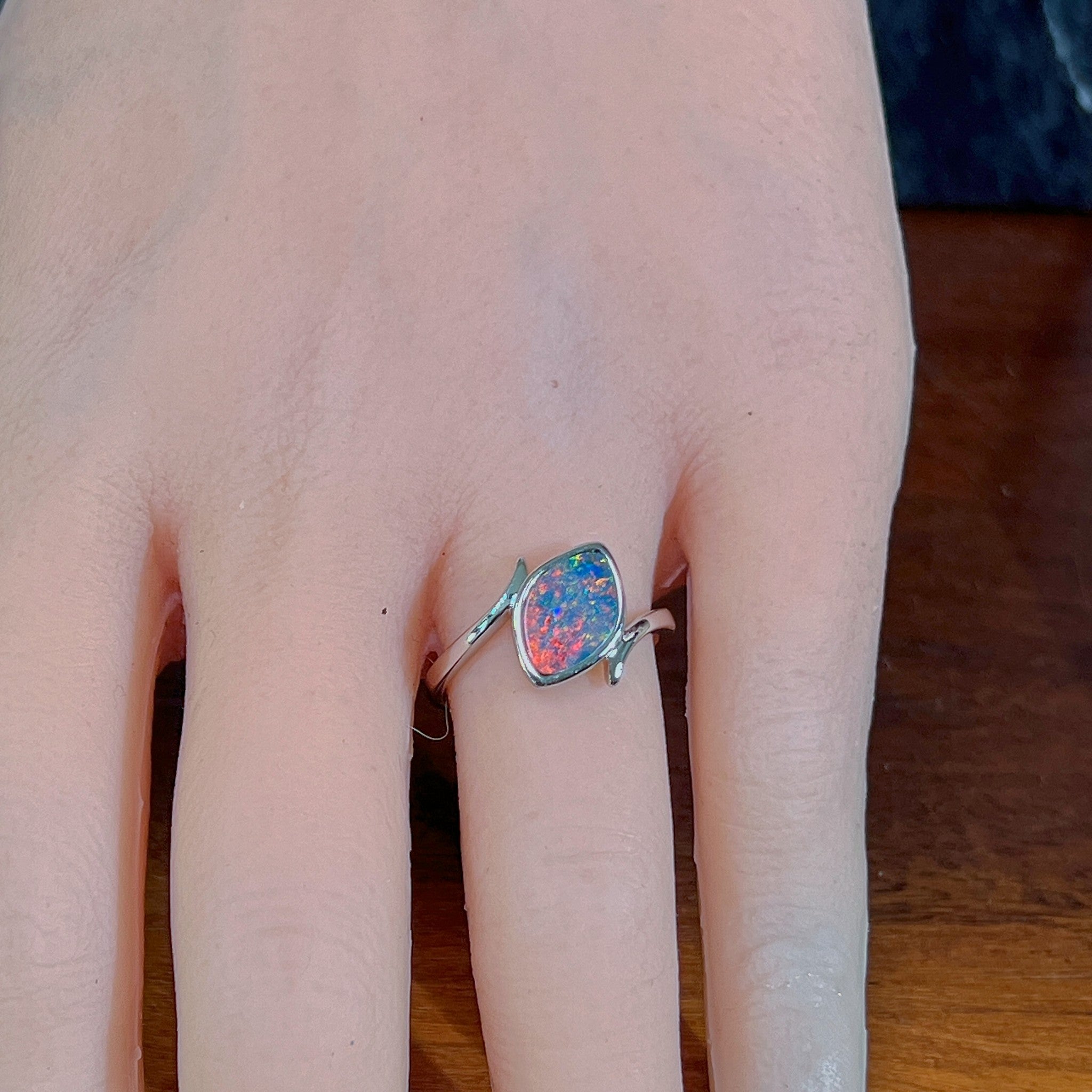 Marquise opal doublet ring in silver worn on the hand, viewed across the fingers