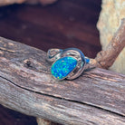 Oval opal doublet in a silver bypass setting, close view of the blue and green flash