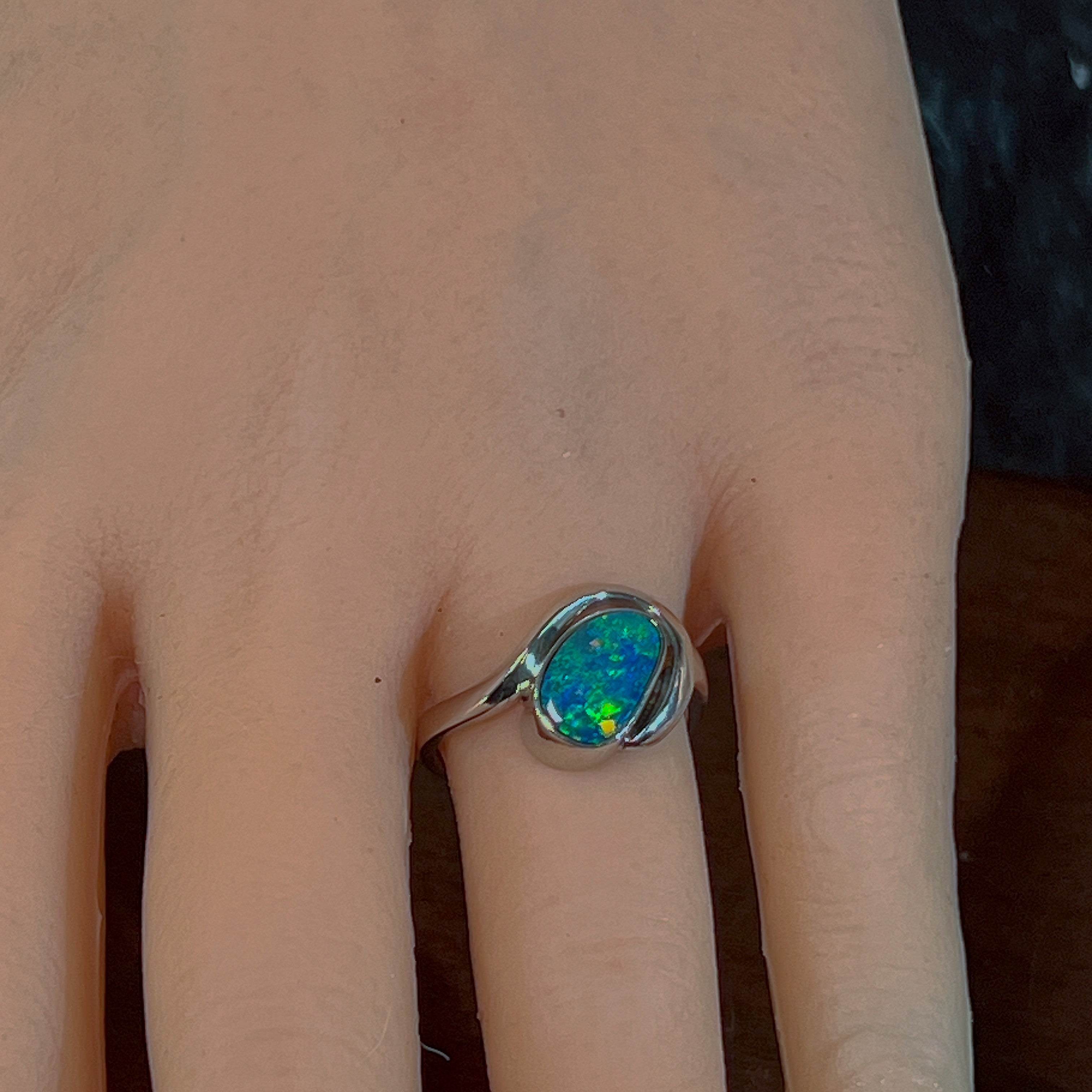 Silver opal doublet bypass ring worn on the hand, showing its scale on the finger