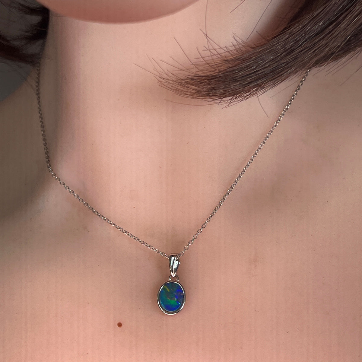 Australian opal doublet pendant worn at the neck, blue, green and red play-of-colour