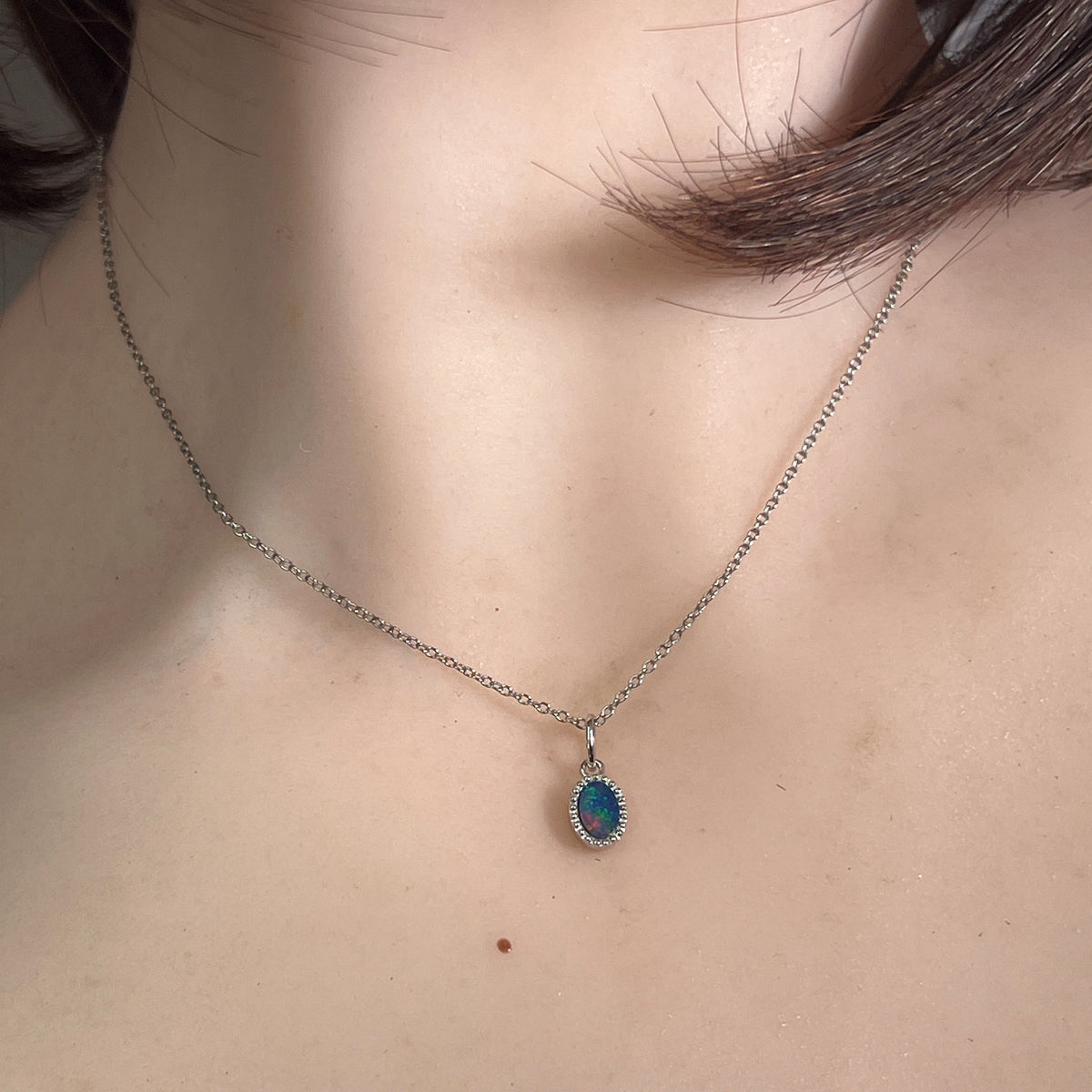 Australian opal doublet pendant worn at the neck, red, blue and green play-of-colour