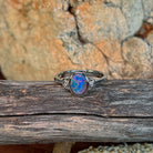 Oval opal doublet ring in silver resting on weathered driftwood