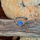 Oval opal doublet ring in silver on driftwood against Australian sandstone