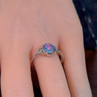 Oval opal doublet ring in silver worn on the hand, full view across the fingers