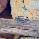 Horizontal oval opal doublet ring in silver on driftwood against Australian sandstone