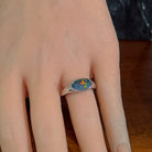 Horizontal oval opal doublet ring in silver worn on the hand, viewed across the fingers