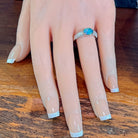 Oval opal doublet ring on a pave silver band worn on the hand, viewed across the fingers