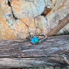 Slanted oval opal doublet ring in silver resting on weathered driftwood