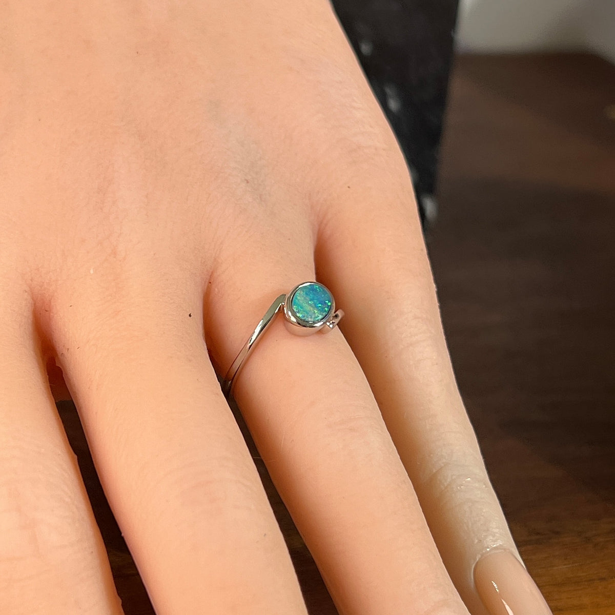 Slanted oval opal doublet ring in silver worn on the hand, showing its scale on the finger