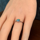 Slanted oval opal doublet ring in silver on the hand, angled to catch the blue, red and green play of colour
