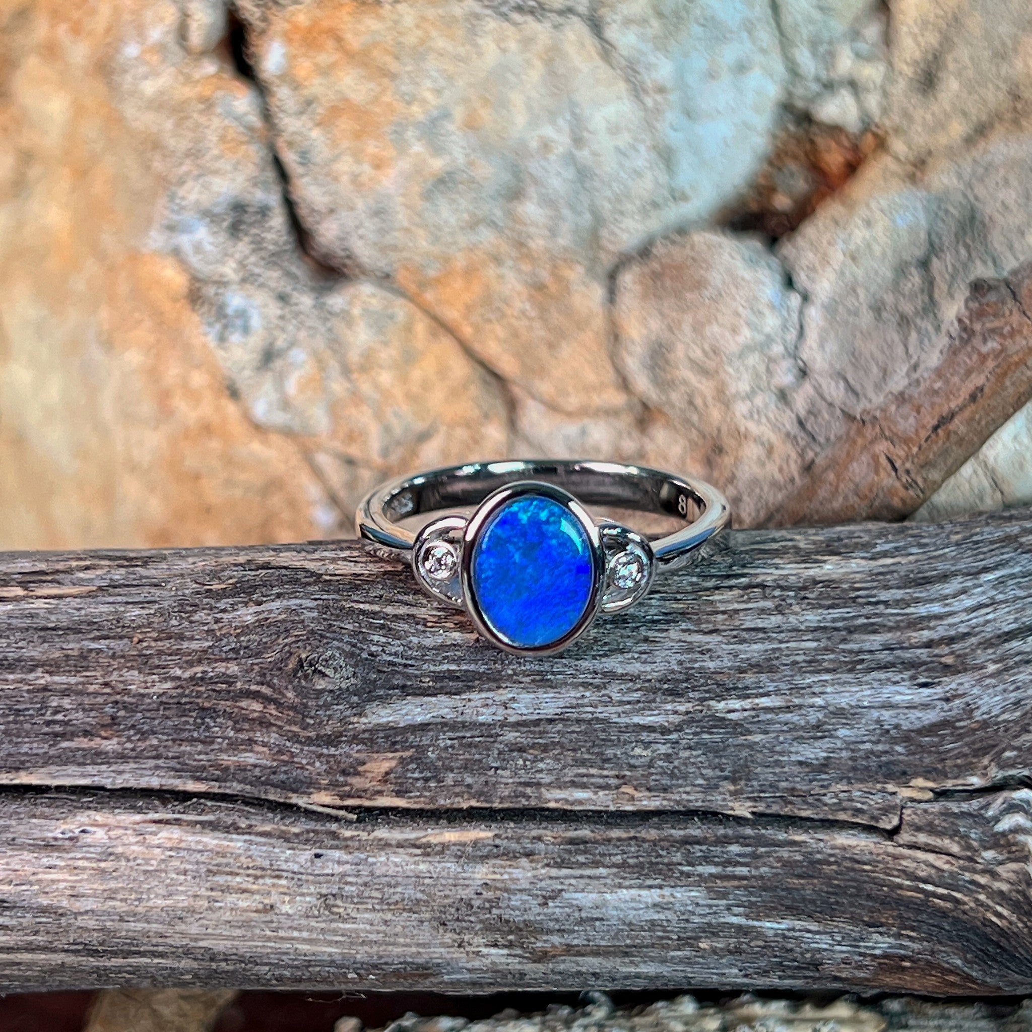 Blue opal doublet ring in silver resting on weathered driftwood