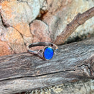 Blue opal doublet ring in silver on driftwood against Australian sandstone