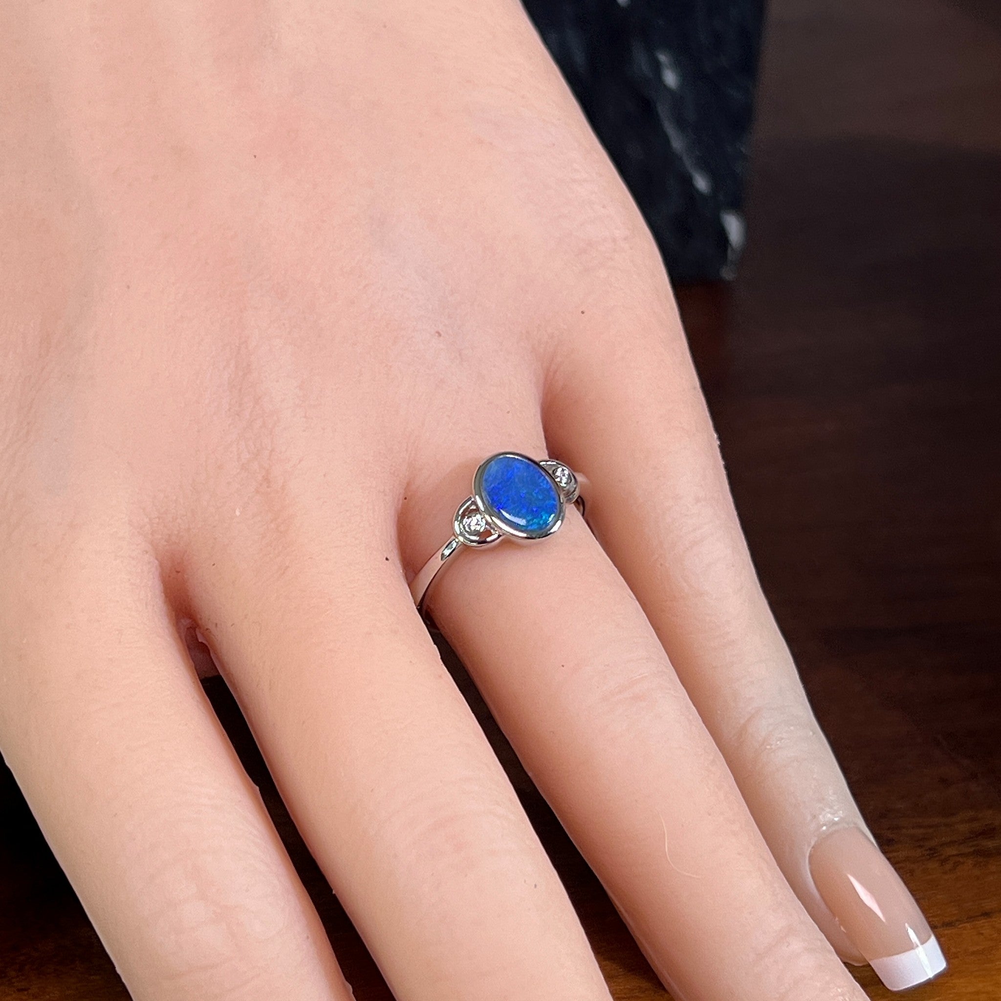 Blue opal doublet ring in silver worn on the hand, showing its scale on the finger