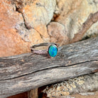Oval opal doublet ring with zirconia shoulders on driftwood against Australian sandstone