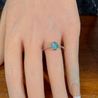 Oval opal doublet ring in silver worn on the hand, viewed across the fingers