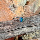 Oval opal doublet solitaire ring in silver on driftwood against Australian sandstone