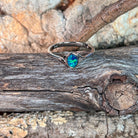 Deep green opal doublet ring in silver resting on weathered driftwood