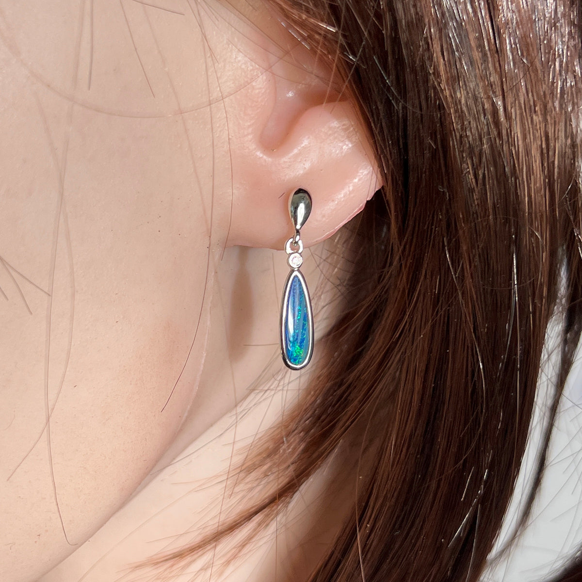 pear-shaped Australian opal doublet earrings in sterling silver, worn on the ear
