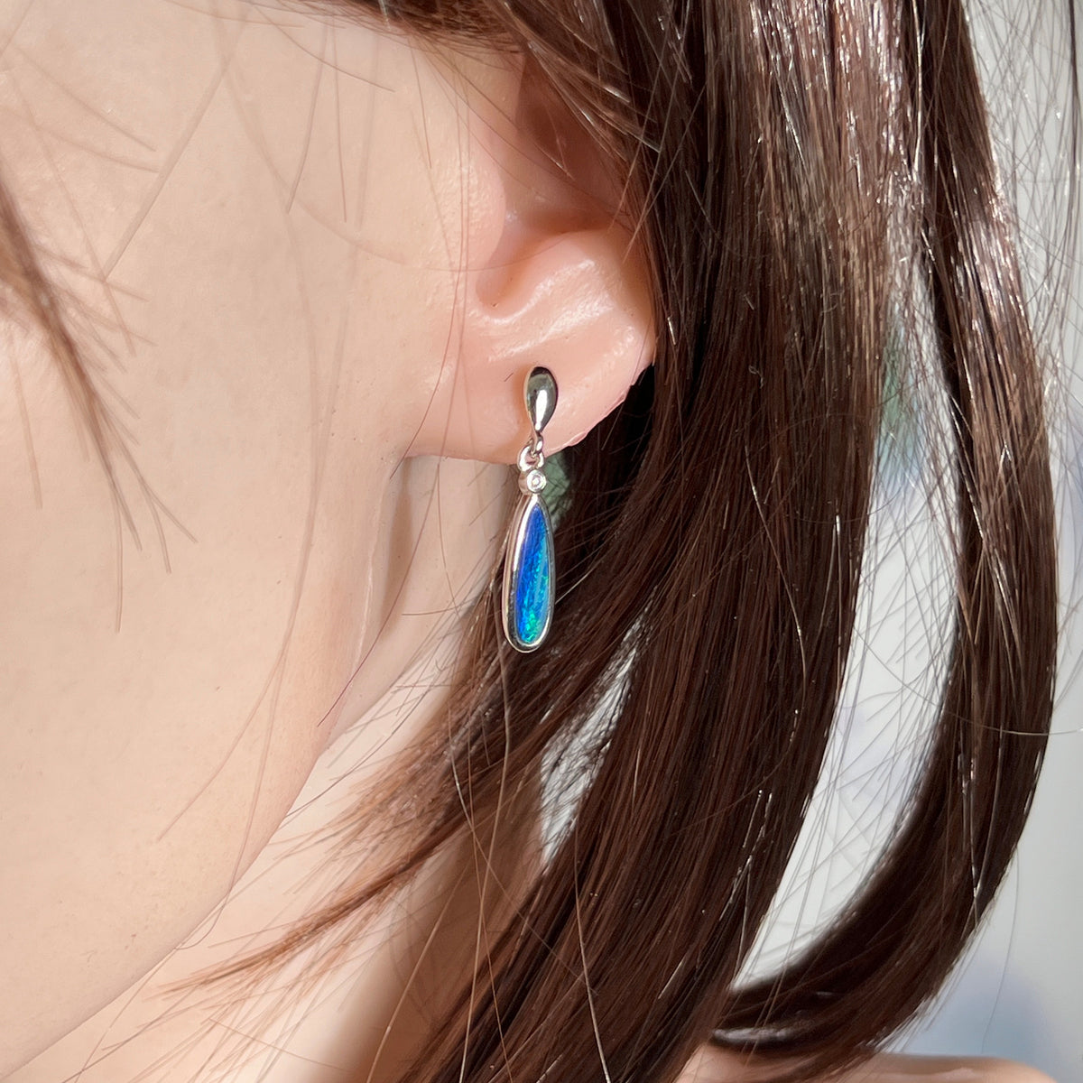 Australian opal doublet earrings worn on the ear, blue and green play-of-colour