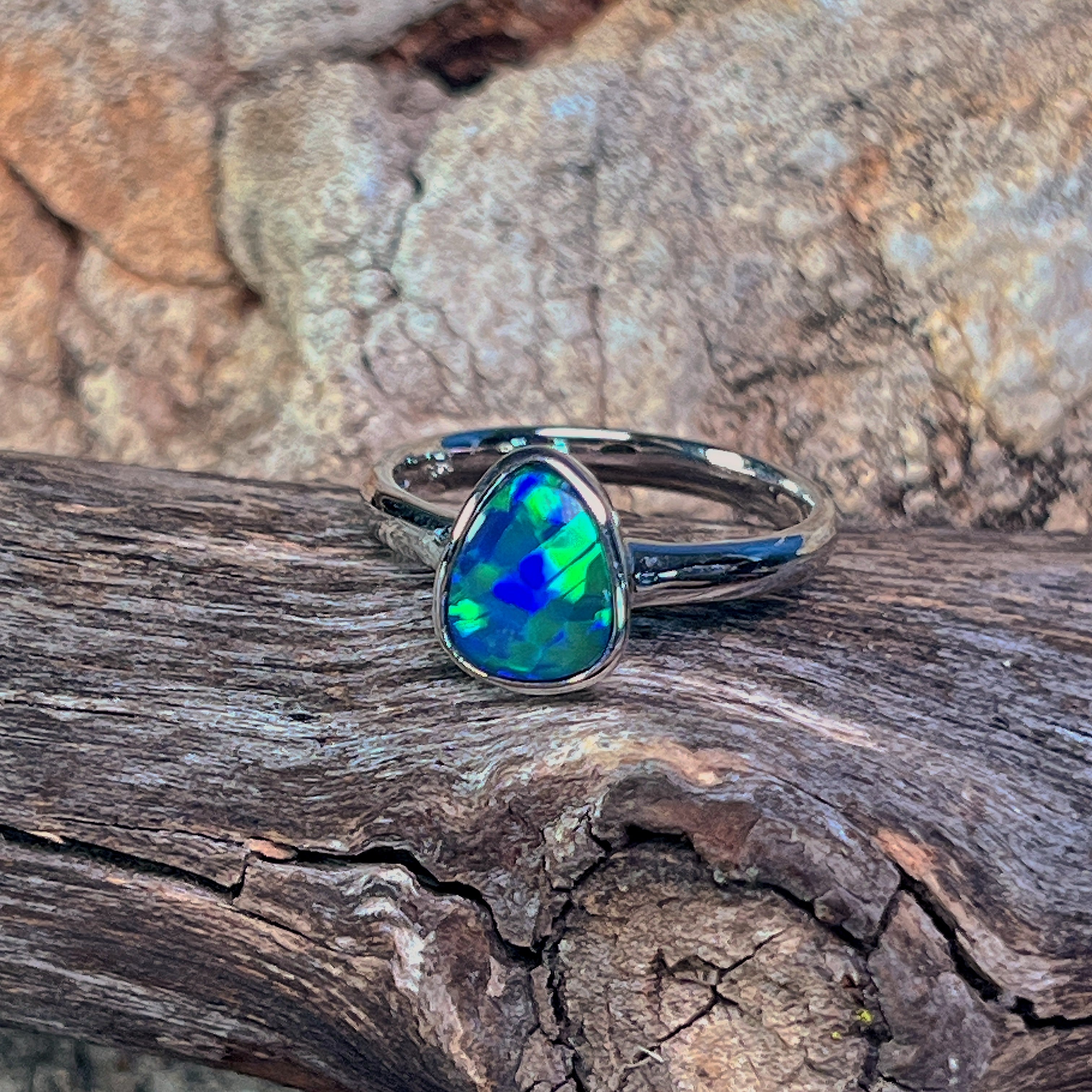 Bezel-set pear-shaped opal doublet in sterling silver, close view of the play-of-colour