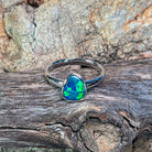 Sterling silver pear opal doublet solitaire ring angled against driftwood