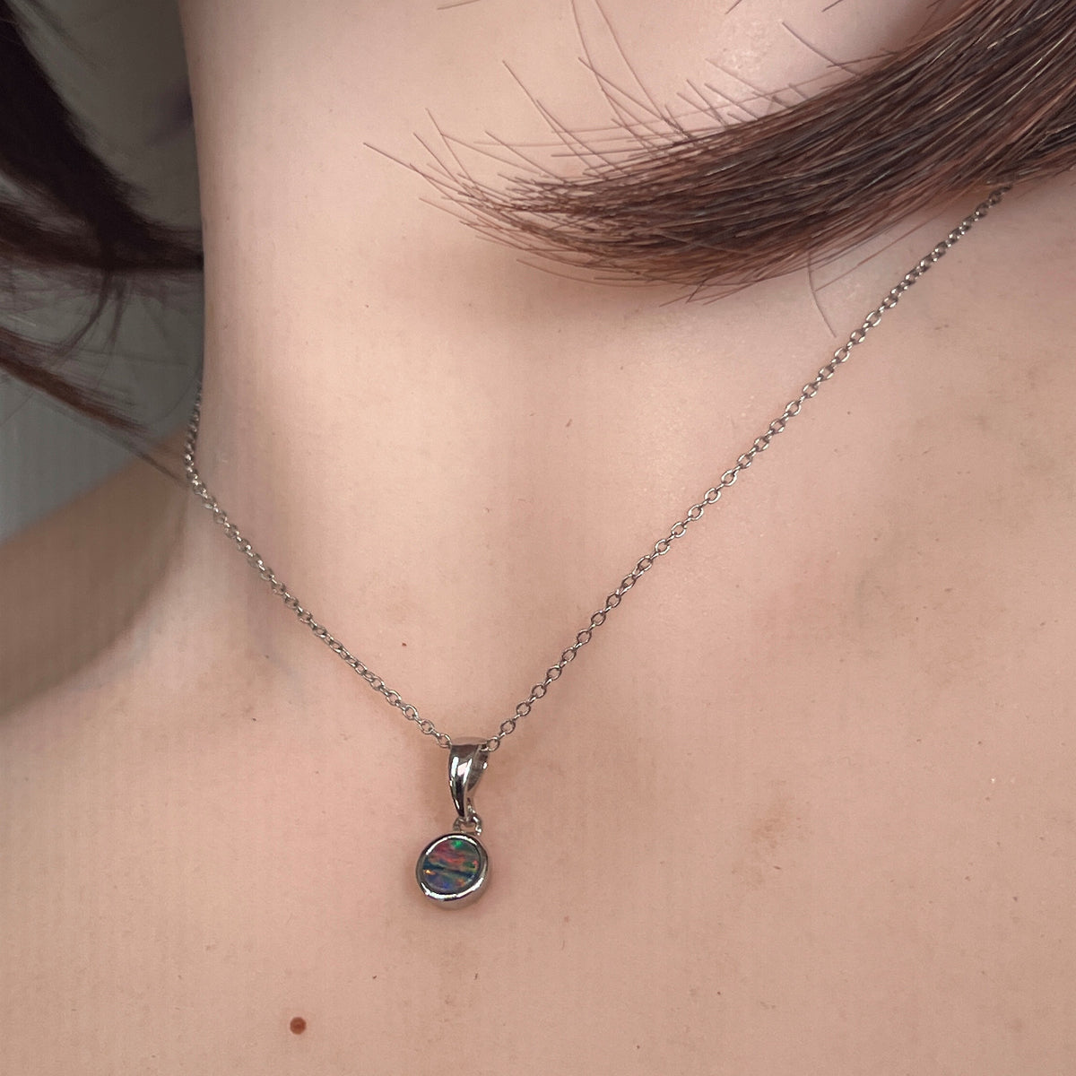 Australian opal doublet pendant worn at the neck, sterling silver, 5mm round stone