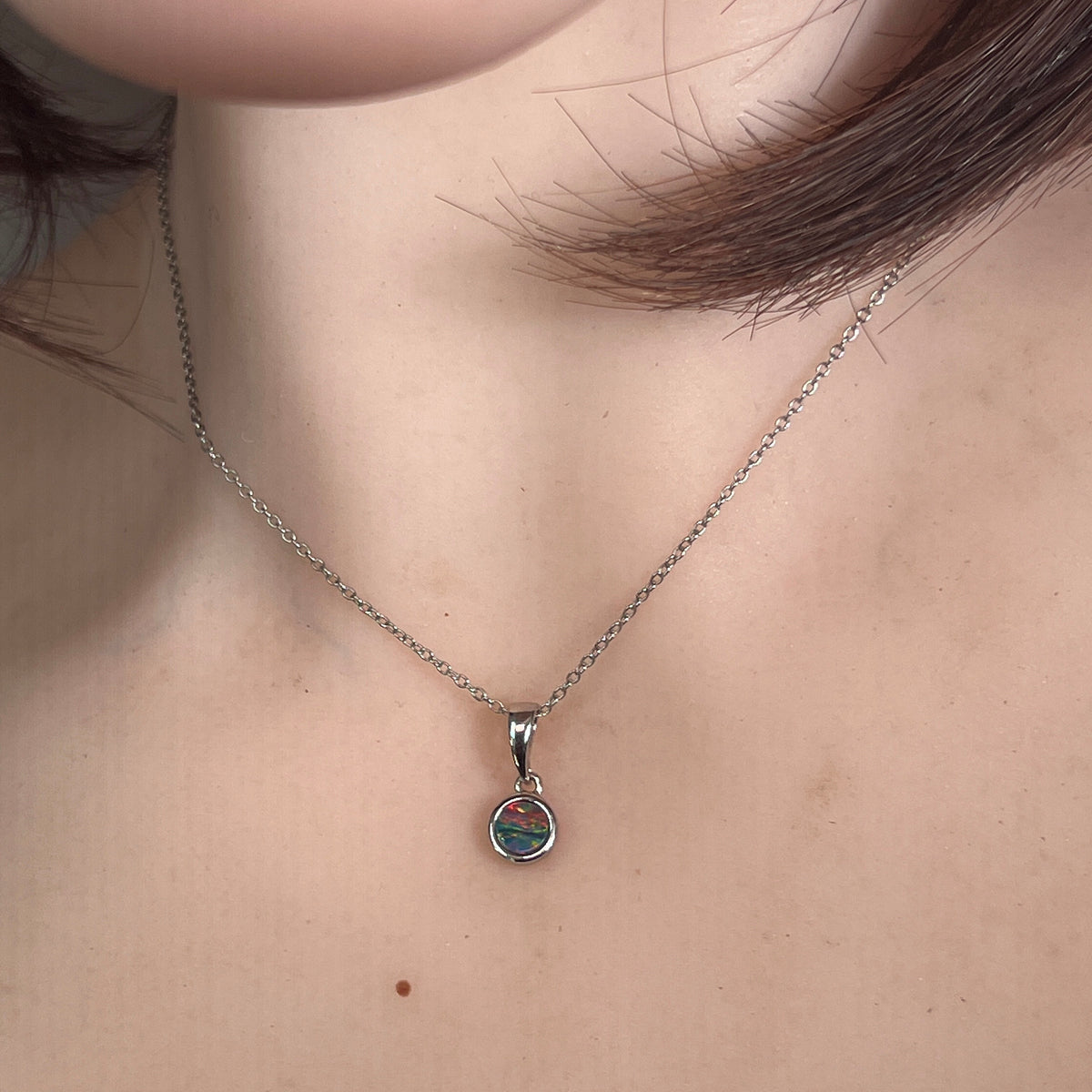round Australian opal doublet pendant worn, sterling silver, red, blue and green