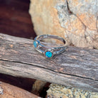 Silver ring with two round opal doublets photographed in profile on driftwood, showing the setting