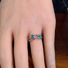 Silver ring with two round opal doublets worn on the hand, viewed across the fingers