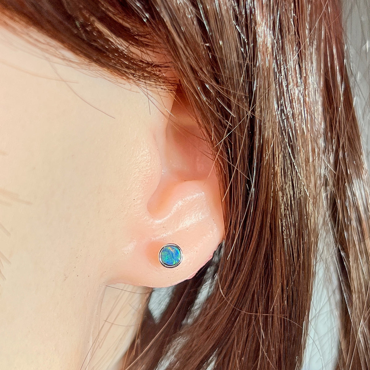 5mm round Australian opal doublet earrings worn on the ear, sterling silver