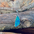 Sterling silver triangle opal doublet pendant hanging against weathered driftwood