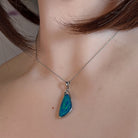 Wing-shaped opal doublet pendant worn at the neck, close view on the chain