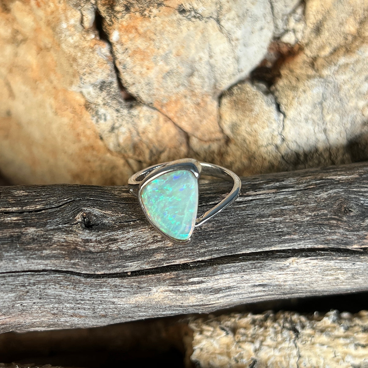 Half bezel set triangular crystal opal ring, sterling silver, solid Australian opal 1.8ct, on weathered timber