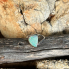 Green and blue solid crystal opal 13x10mm, triangular, sterling silver cross over ring, side view on timber