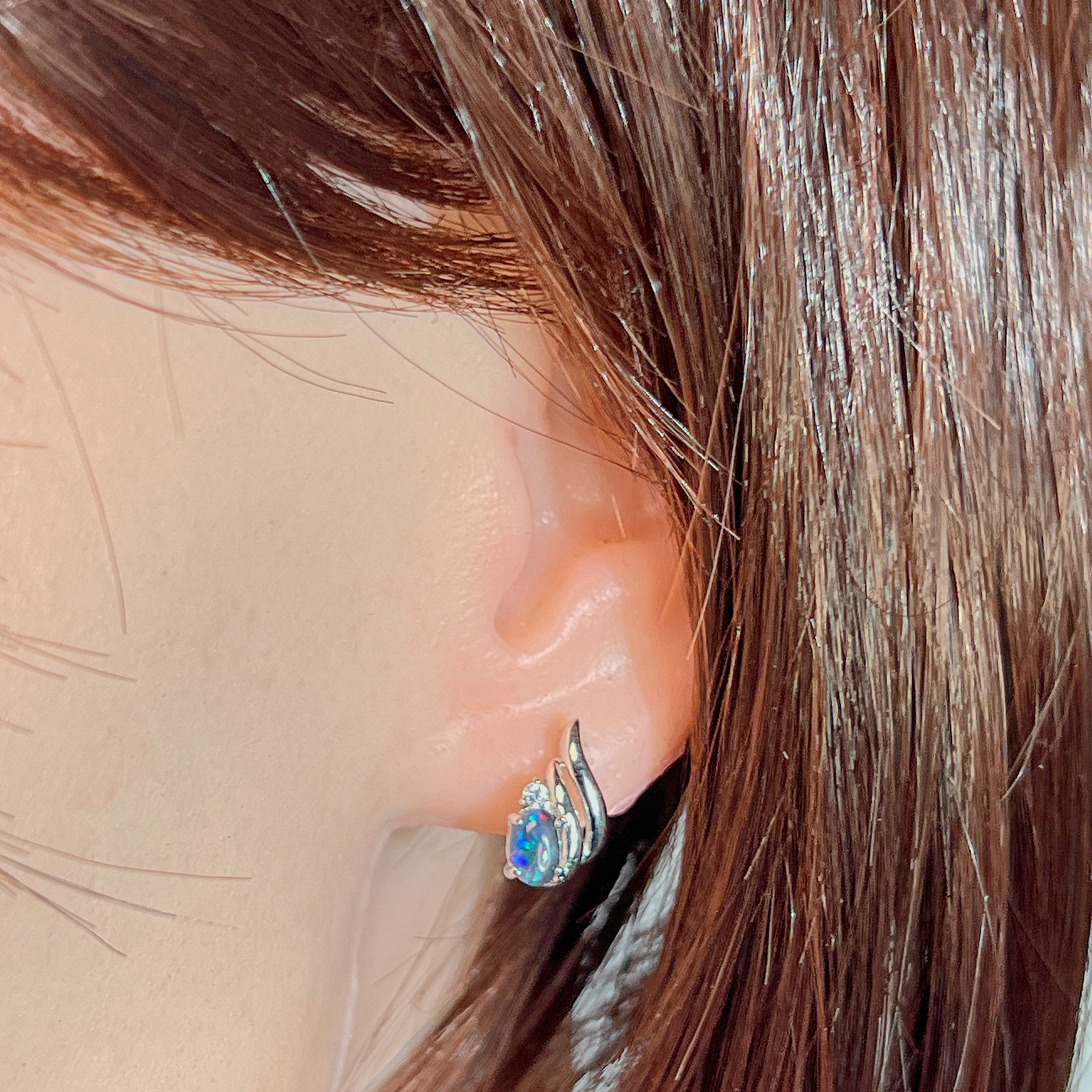 Silver opal triplet earring with swirl detail worn on the ear, showing its scale