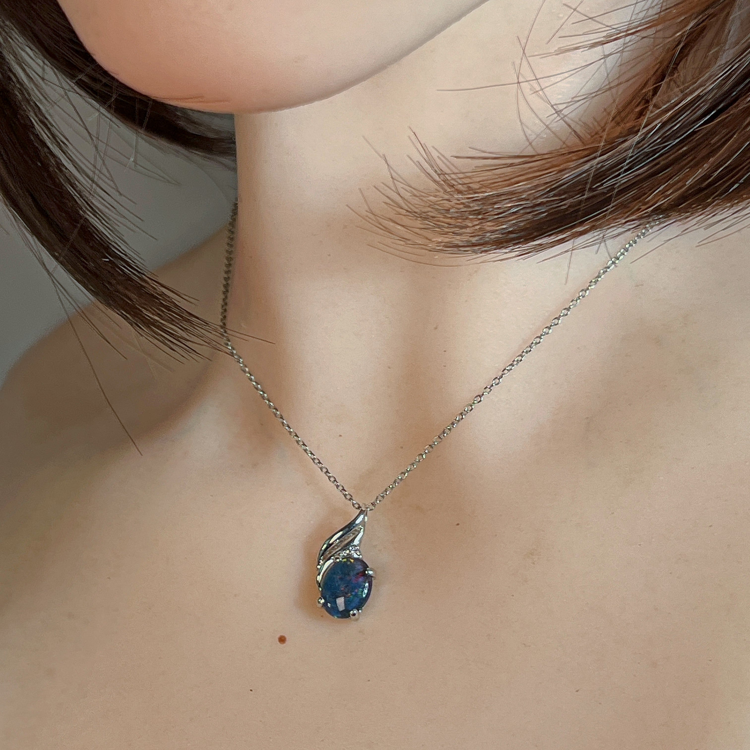 Oval opal triplet pendant worn at the neck, showing its scale on the collarbone