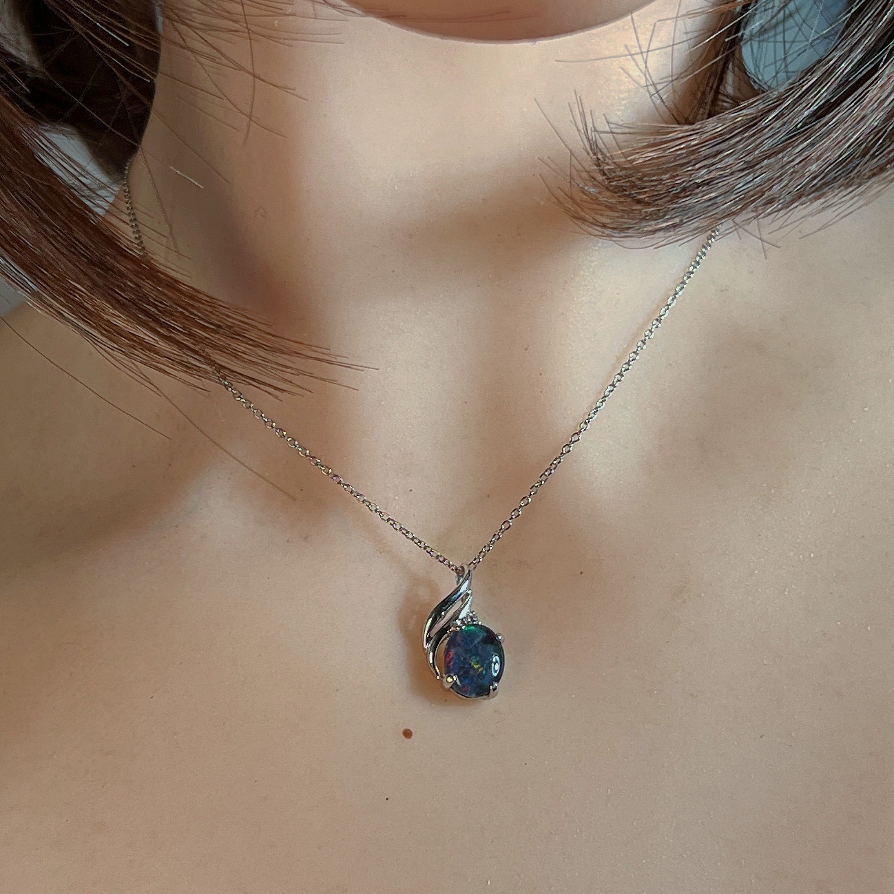 Silver opal triplet pendant with swirl setting worn at the neckline, close view