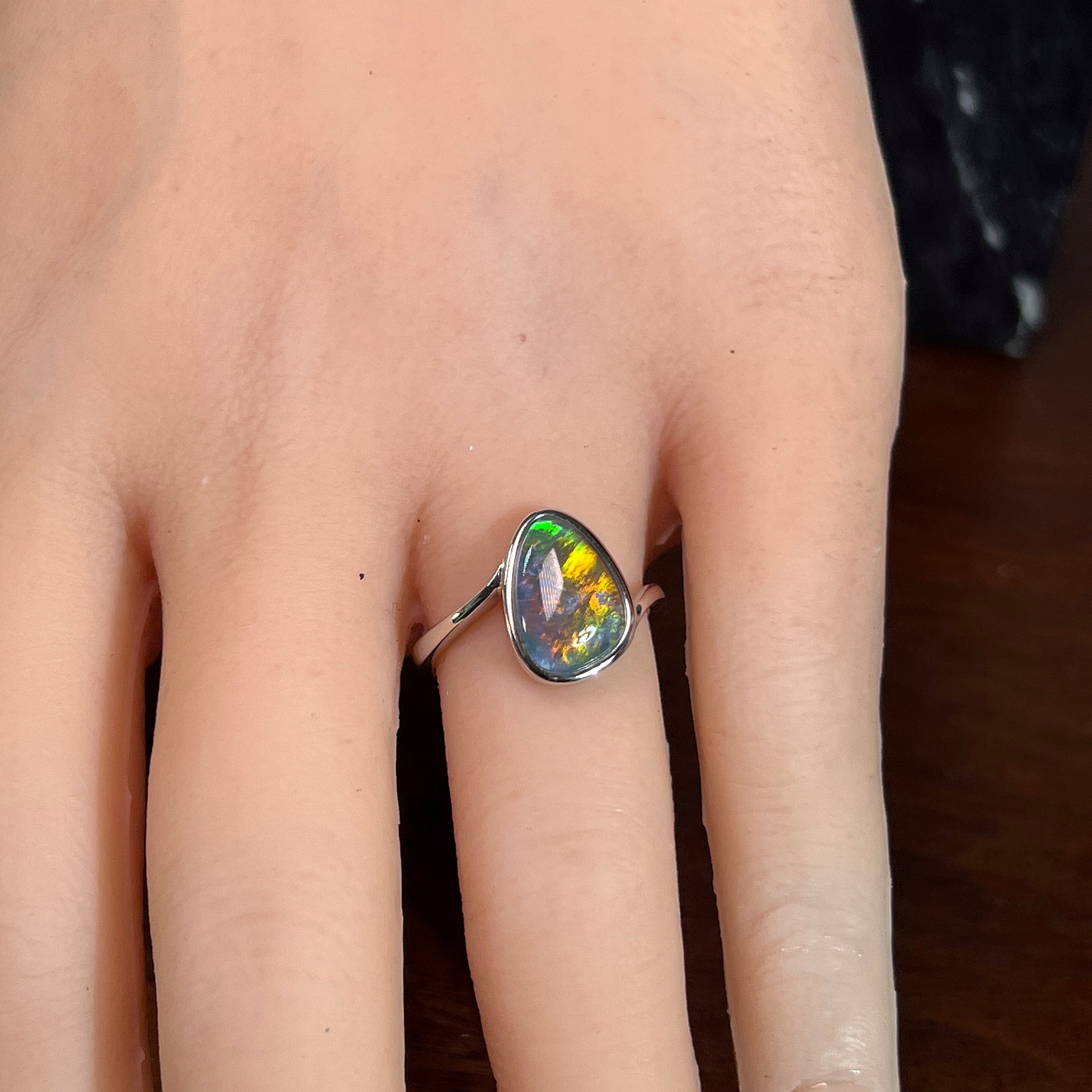 Australian opal triplet ring worn on the hand, red, yellow, blue and green play-of-colour