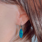 White gold opal doublet drop earring worn on the ear, showing its length on the earlobe