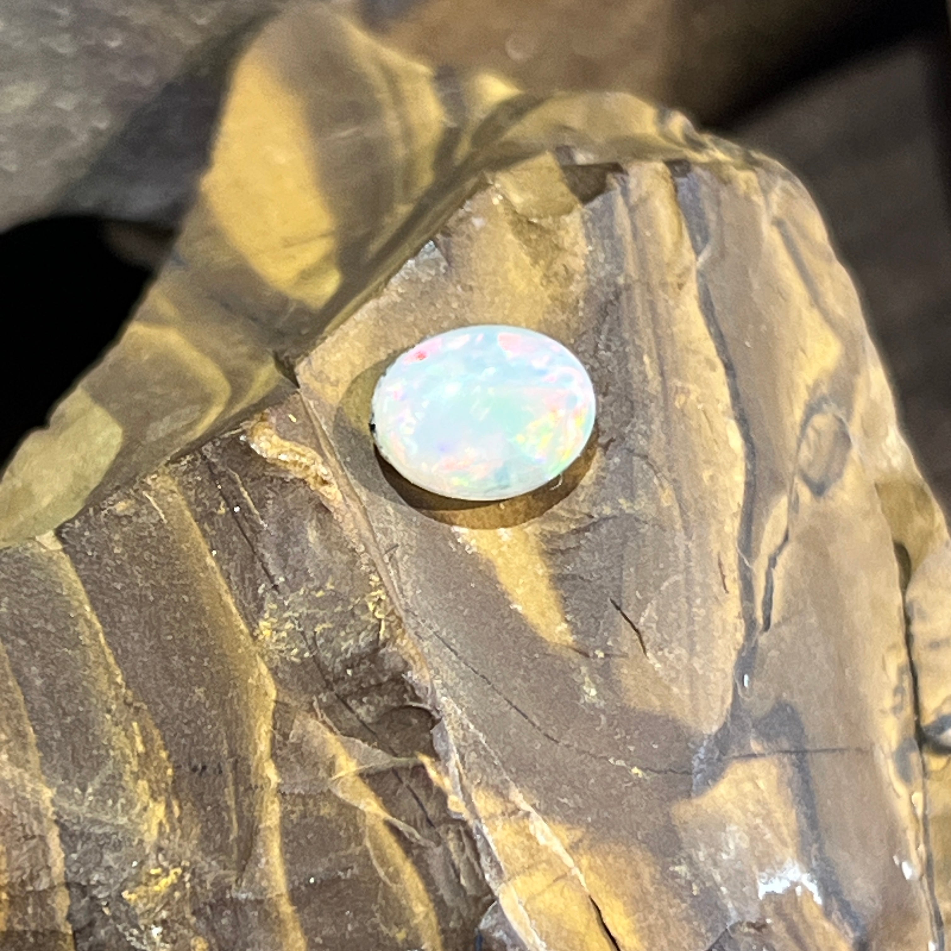 Australian white opal oval resting on ironstone, soft pastel play of colour
