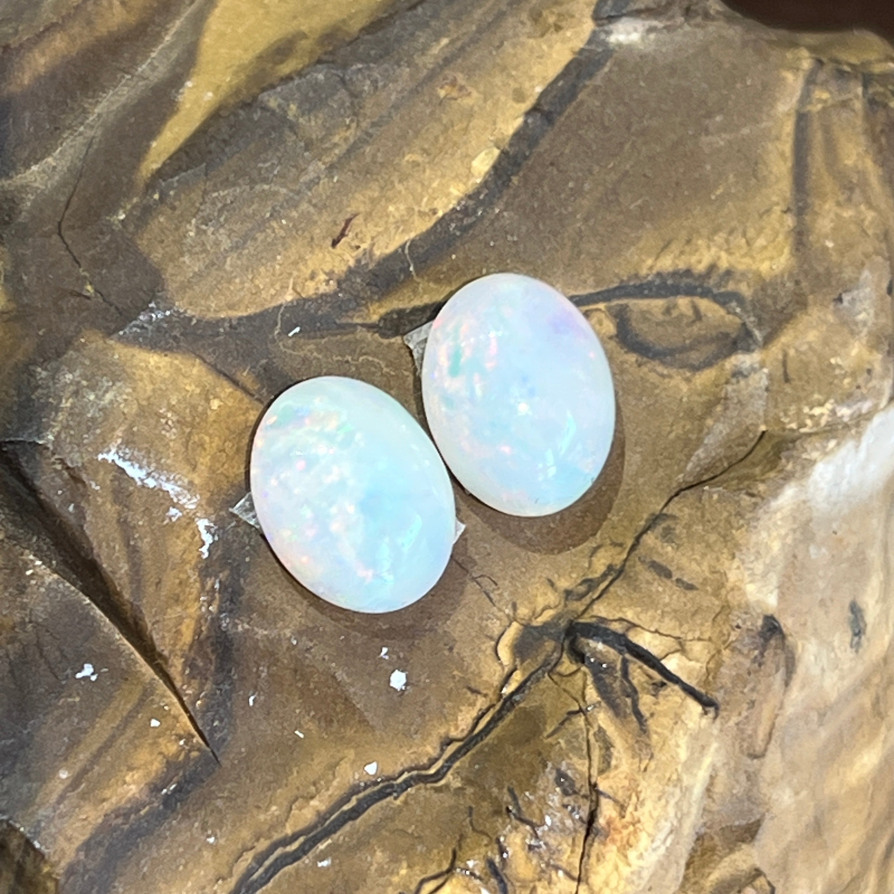 Two Australian white opal cabochons together, the right stone showing stronger green and blue fire