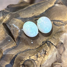 Pair of Australian white opals face up in sunlight, both showing green and blue pinfire