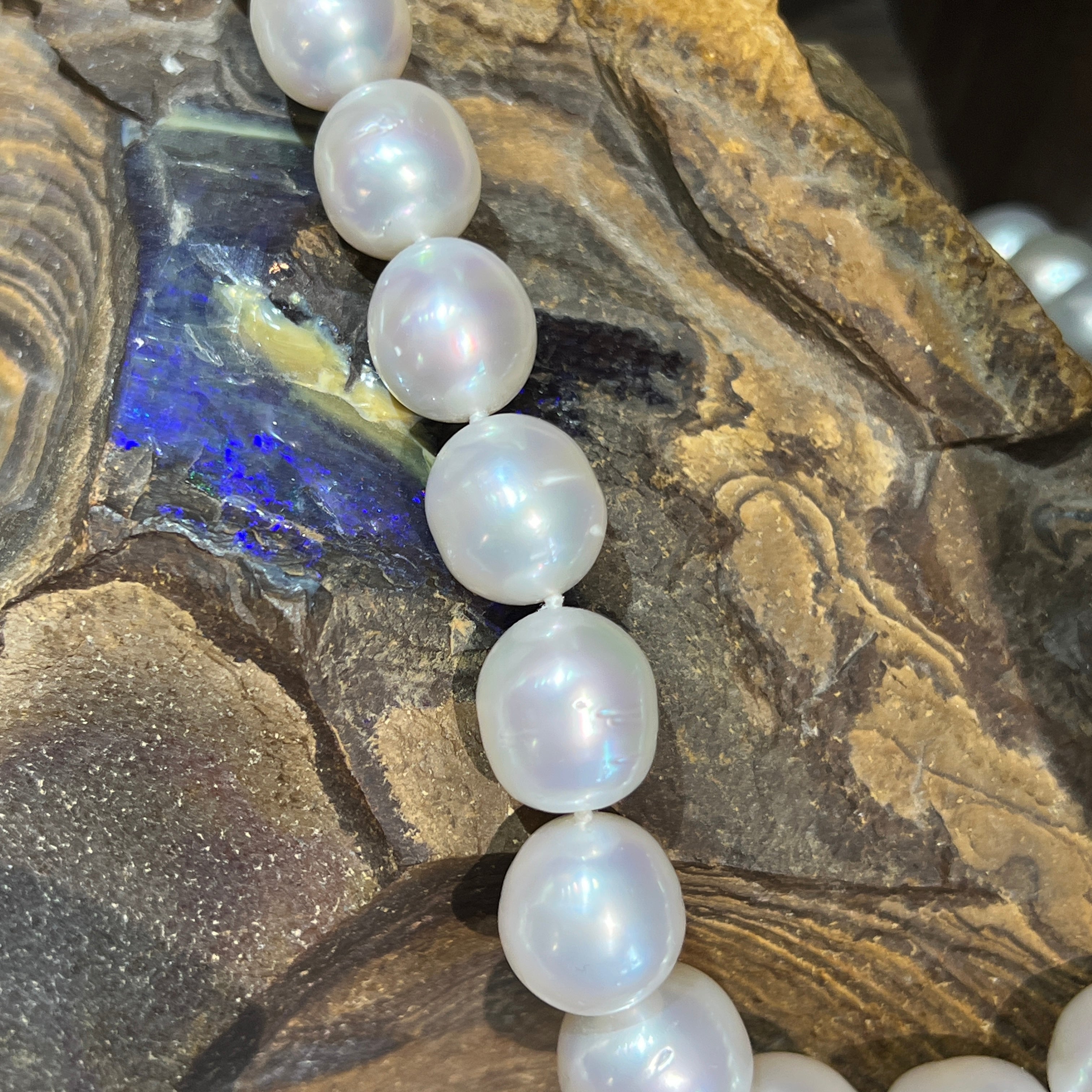White South Sea pearl strand curving across ironstone with blue opal colour in the rock