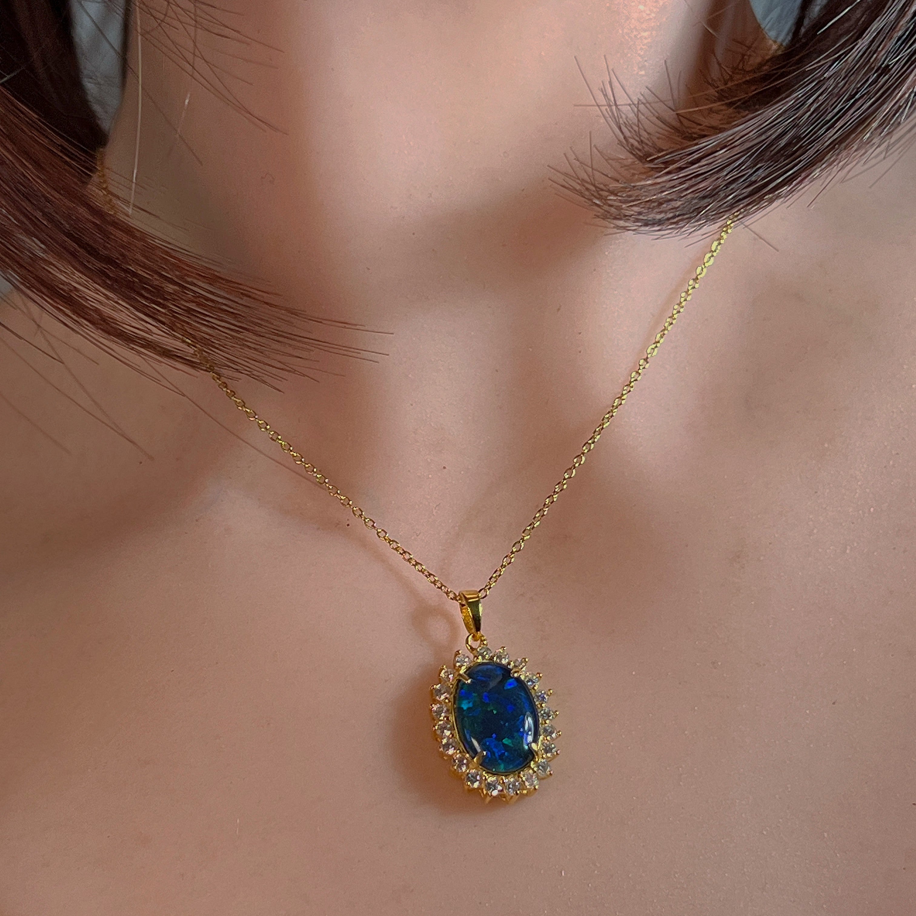 Deep blue opal triplet halo pendant worn at the neckline, close view